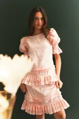 Falda corta de lino color rosado, con diseño de volados escalonados con detalle de tablitas que aportan textura y movimiento.