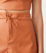 Short de material sintético color naranja, con cintura alta y lazo ajustable.
