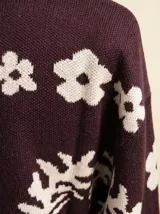 Cardigan de punto color cacao con estampado de flores en color crema, cuello tipo polo, cierre frontal con botones y puños acanalados.