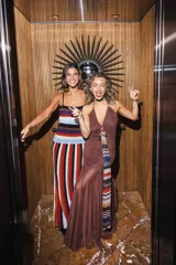 Vestido largo negro de encaje con escote profundo halter, espalda abierta, detalles fruncidos al cuerpo y falda larga semitransparente con tiras largas para atar.