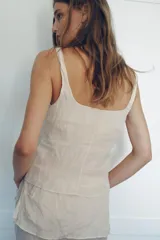 Top de viscosa con diseño efecto arrugado, escote redondo, tirantes finos y cierre frontal con botones ocultos.