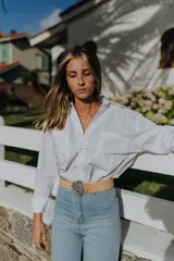 Camisa blanca de mangas largas con cuello clásico y cierre con botones.