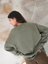 Sweater de hilo de algodón en color beige con diseño tejido de la bandera de Uruguay en el centro. Presenta cuello redondo, mangas largas y un corte holgado.