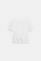 Camiseta blanca de manga corta abullonada y cuello redondo, con detalles de bordados perforados y bajo con doble volante.