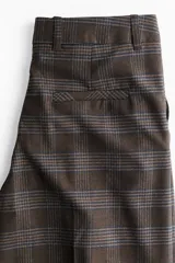 Pantalón sastrero de corte holgado y pierna ancha, con diseño a cuadros en tonos marrones. Presenta pinzas frontales, cintura estándar con cierre oculto, bolsillos laterales al bies y bolsillos traseros insertados.