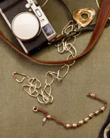 Pulsera artesanal compuesta por una serie de cuentas metálicas irregulares ensartadas en un hilo de algodón natural. Diseño rústico y minimalista.