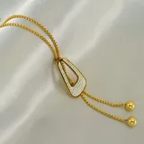Collar estilo lariat de acero quirúrgico con baño de oro 18k, con dije triangular decorado con circonias y terminales de bolitas doradas.
