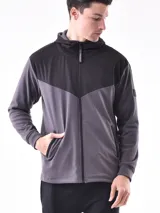 Campera deportiva con cierre frontal, capucha y diseño de bloques de color. La parte superior (hombros y capucha) es negra, y el cuerpo y mangas son de color azul vibrante, con un corte diagonal que separa ambos colores.