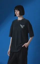 Remera de manga corta con cuello redondo y calce oversize, confeccionada en algodón premium con efecto de lavado nevado. Presenta una estampa gráfica en la espalda con diseño de palomas y texto alusivo.
