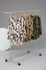 Camisa de manga larga con estampado retro en tonos marrones, beige y verde. Tiene cuello mao y la parte trasera más larga que la delantera.