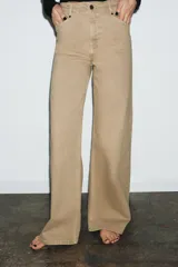 Jeans de tiro alto con corte wide leg y largo completo. Presenta diseño de cinco bolsillos, cintura con trabillas y cierre frontal con cremallera y botón.