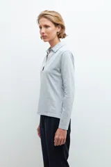 Remera de manga larga color gris melange, con cuello polo y escote en V pronunciado.