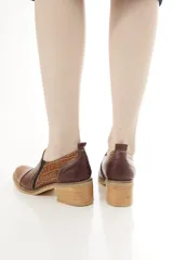 Zapatos de cuero negro con textura de cocodrilo en la puntera y el talón, de corte bajo, con elásticos laterales y taco cuadrado.
