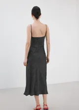 Vestido midi de estilo lencero color negro con estampado de lunares blancos, escote en V con detalle de encaje negro, tirantes finos y diseño entallado.
