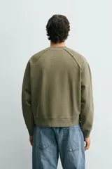 Sudadera relaxed fit color verde militar con efecto lavado, cuello redondo y manga larga. Confeccionada en tejido de algodón con interior afelpado y acabados en rib.