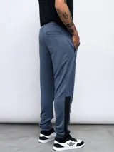 Pantalón de jogging Umbro confeccionado en poliéster, con diseño de bloques de color en azul y negro, cintura elástica con cordón ajustable y puños en los tobillos.