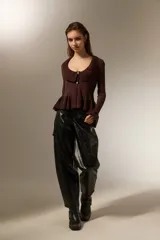 Pantalon de eco-cuero negro con acabado brillante, diseño tipo barrel de tiro alto, con bolsillos laterales y cierre frontal.