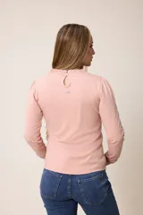 Remera de manga larga color rosado, con cuello redondo y puños con detalle de volados fruncidos.