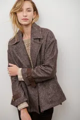 Chaquetón de lana color bordó con diseño de espiga y motas blancas. Tiene solapa, doble abotonadura frontal, mangas largas con detalle de correa y hebilla en los puños.