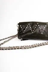 Bandolera de cuero negra con diseño en zigzag de tachas plateadas y asa de cadena metálica.