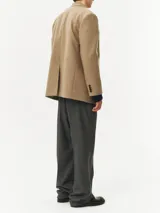 Blazer color marrón claro confeccionado en lana, de corte recto, con solapas de muesca, cierre con dos botones y bolsillos con solapa.