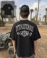Remera negra de manga corta y corte oversize, con estampa gráfica en blanco en el frente y en la espalda con diseño de tipografía y escudo heráldico.