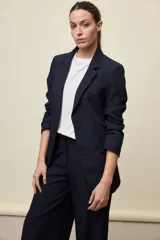 Blazer negro de líneas clásicas y silueta sastrera, con solapas y estructura definida.