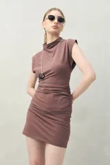 Vestido corto de punto color marrón, sin mangas, con cuello cerrado y hombros levemente estructurados. Presenta frunces laterales que realzan la figura.