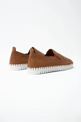 Zapatilla tipo slip-on de cuero color tostado, con textura perforada y suela de goma blanca con diseño dentado.