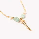 Colgante con cadena dorada de eslabones, adornado con perlas, piedras semipreciosas de color verde claro y un dije dorado en forma de cuerno o colmillo.
