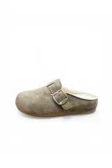Zueco de gamuza sintética color kaki con forro interno de corderito sintético, tira ajustable con hebilla metálica y suela plana.