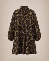 Vestido corto de lino con estampado floral en tonos tierra, verde y marrón. Presenta cuello redondo, mangas tres cuartos con volumen y silueta holgada.