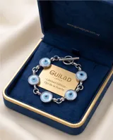 Pulsera de eslabones de acero con dijes circulares tipo ojo turco en tonos celestes y blancos.