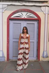 Chaleco largo de tejido de punto con diseño de chevron en tonos crema, marrón y bordó. Presenta un cierre frontal con ganchito metálico y aberturas laterales.