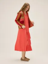 Vestido midi de morley color coral, con escote en V, sin mangas y diseño holgado con volados fruncidos en el lateral de la falda.