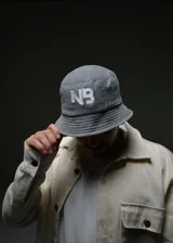 Gorro bucket gris con el logo bordado "NB" en color blanco en el frente.
