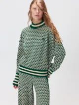 Buzo polera Mutma Tivo de punto jacquard con texturas inspiradas en la naturaleza. Presenta cuello y puños acanalados en tonos tostado y crudo.