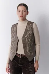 Chaleco marrón de simil cuero con bordado en color crema, cuello en V y cierre frontal con botones.