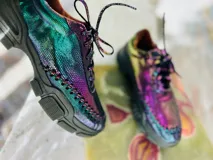Zapatillas bajas con cordones, capellada con textura de escamas en tonos iridiscentes que varían entre verde, azul y violeta.