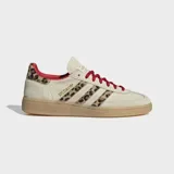 Championes Adidas modelo Handball Spezial, con diseño clásico de perfil bajo. Presentan una base en tono beige con detalles de estampado animal print en las icónicas tres tiras laterales y en el talón. Incluyen cordones en color rojo vibrante, forro interior a tono y suela de caucho tipo goma.