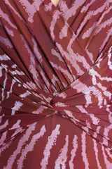 Malla enteriza con estampado animal print tipo cebra en tonos bordó y rosado, con escote en V cruzado y detalle de nudo drapeado en el centro.