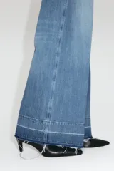Jean de tiro alto en denim de algodón con leve stretch. Presenta piernas amplias, corte holgado, bolsillos tipo parche en la parte frontal y raya marcada a lo largo de las piernas. Incluye cierre y botón metálico.