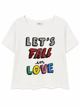 Remera blanca de manga corta con cuello redondo y estampa frontal de lentejuelas con la frase "LET'S FALL in LOVE".