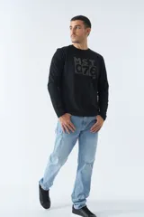 Remera de manga larga negra con estampado rectangular en el frente con letras grises. Corte recto y cuello redondo.