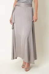 Pollera larga de satén color beige, con diseño amplio, cintura elástica y lazo lateral para anudar.