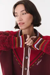Cardigan de punto color bordó con diseño de rayas en cuello y puños en tonos marrón, blanco y celeste. Presenta cierre frontal con botones, mangas con trama trenzada y detalle de logo bordado en el frente.