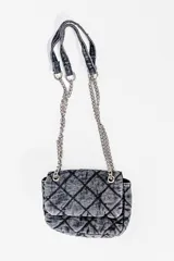 Cartera bandolera de jean negro con diseño acolchado en forma de rombos. Tiene correa de cadena plateada y manija de jean.