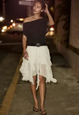 Pollera midi blanca de viscosa con volados irregulares en capas. Se ajusta a la cintura con un cinturón negro con hebilla metálica.