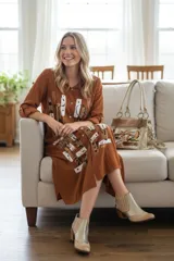 Vestido camisero midi de color marrón terracota, de manga larga, cuello solapa y cierre frontal con botones. Presenta un diseño estampado de estilo artístico abstracto en la parte frontal.