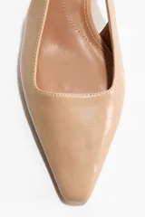 Zapatos destalonados en tejido revestido de color beige, con punta cincelada, tira fina en el talón con elástico y taco kitten.